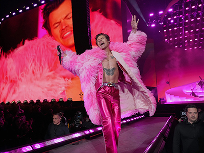 harry styles in a pink furry coat while performing