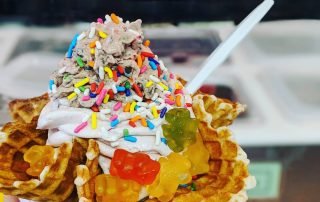 ice cream with gummy bears and sprinkles in a waffle cup