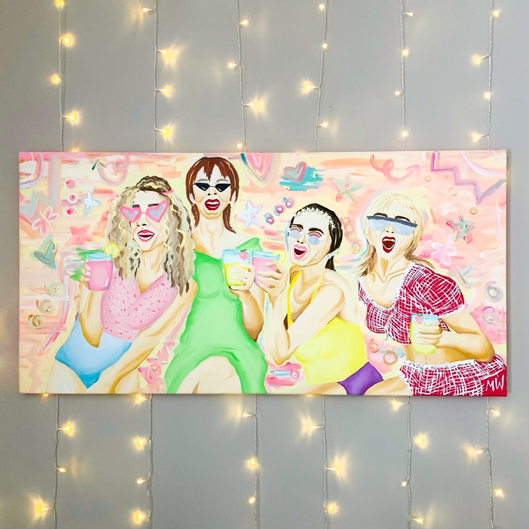 A painting of the Sex in the City cast with drinks in hand, done in bright colors. The canvas hangs on a wall with twinkle lights.